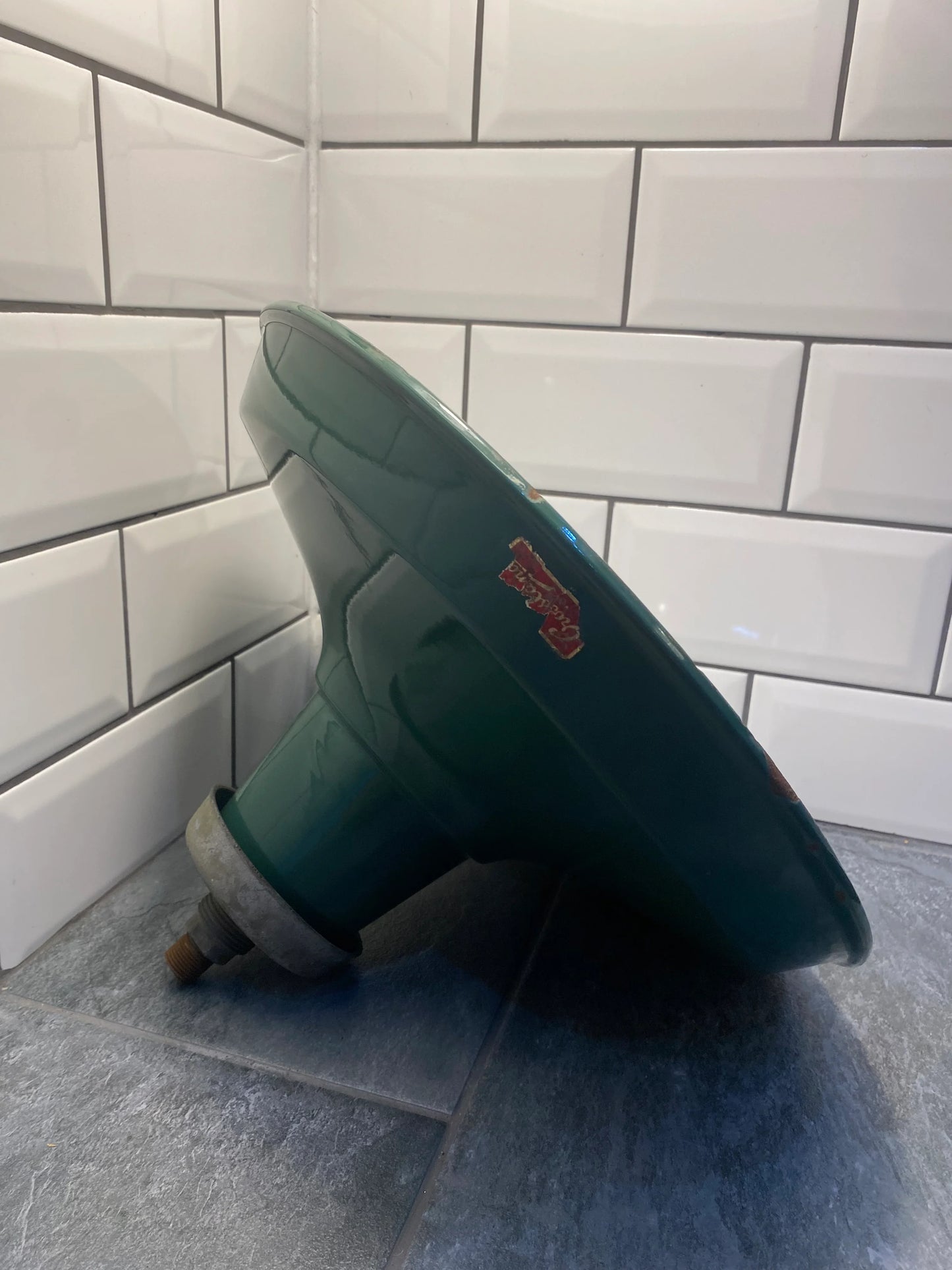 Vintage green industrial enamel light shade with metal fitting on tiled floor