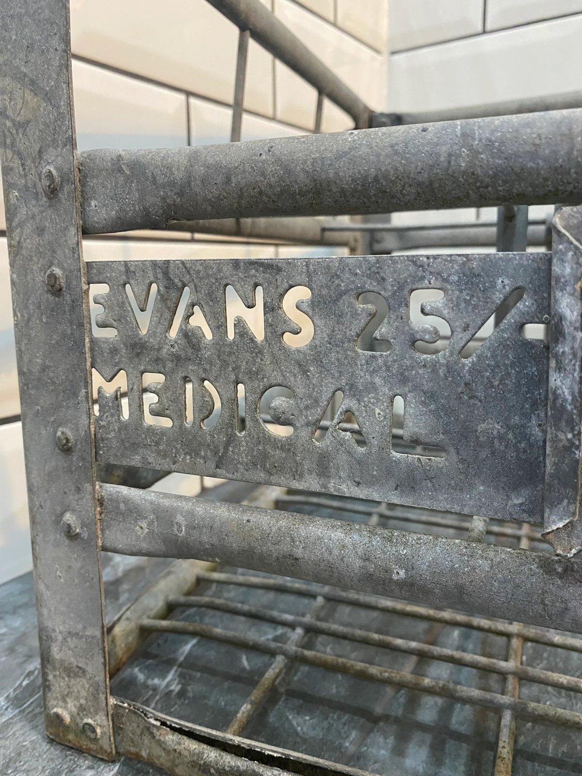 Vintage metal medical storage rack with 'Evans 25/- Medical' cut-out lettering