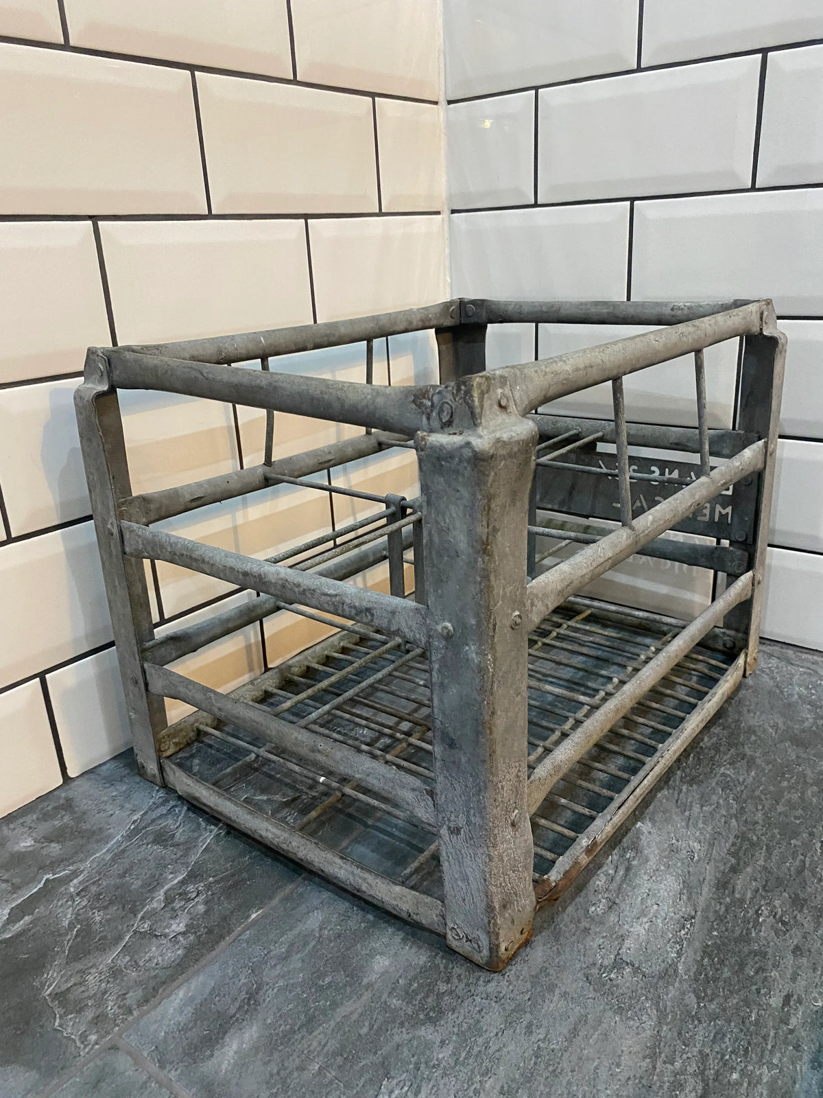 Vintage industrial metal crate on tiled floor against white subway tile wall