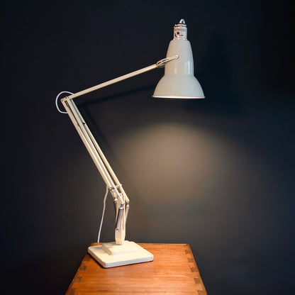 Vintage adjustable cream desk lamp on a wooden table against a dark wall