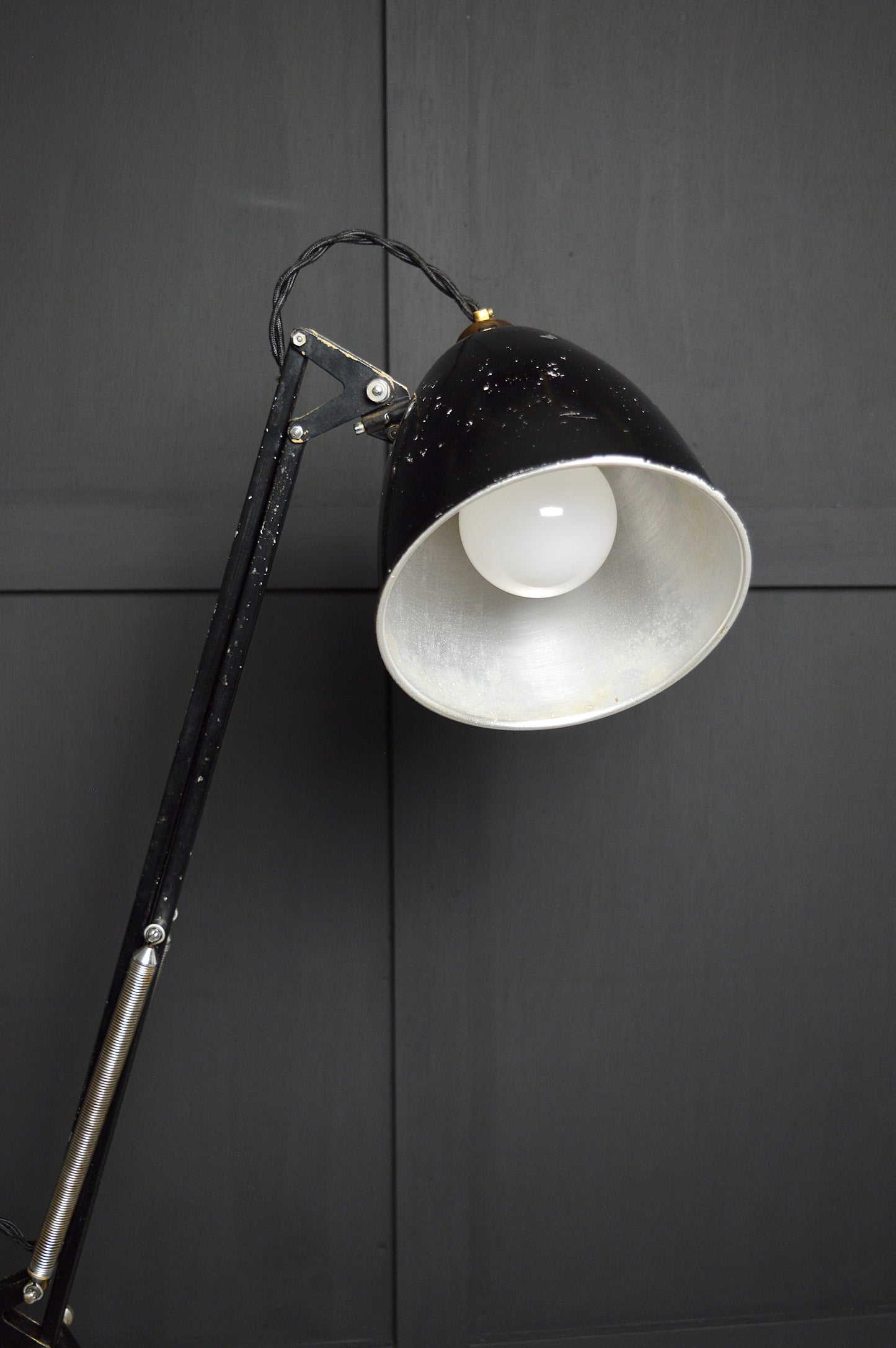 Black floor lamp with white shade against a dark wall