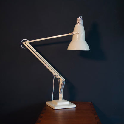 Vintage cream adjustable desk lamp on a wooden table against a dark wall
