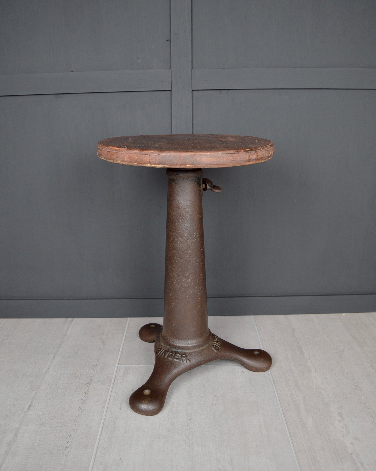 Round stool with a dark brown base against a gray wall.