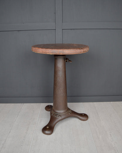 Round stool with a dark brown base against a gray wall.