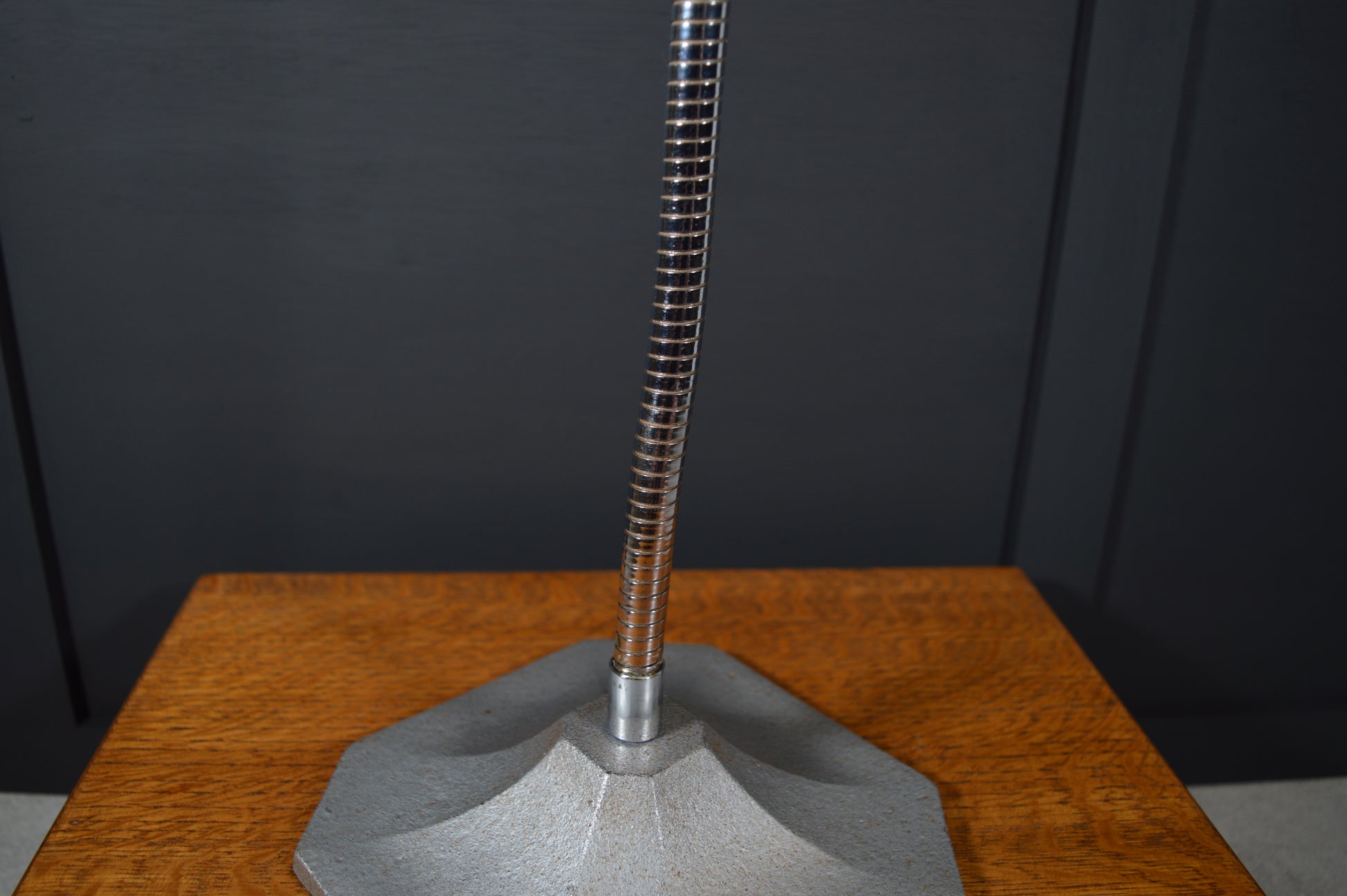 Vintage metal lamp base and flexible stem on wooden table against dark background